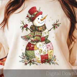 Könnte beinhalten: Ein cremefarbenes Sweatshirt mit einem skurrilen Schneemann-Design. Der Schneemann trägt einen roten Zylinder, einen Patchwork-Schal und einen Patchwork-Körper. Das Design beinhaltet Stechpalmenzweige und den Text "Digital Download".