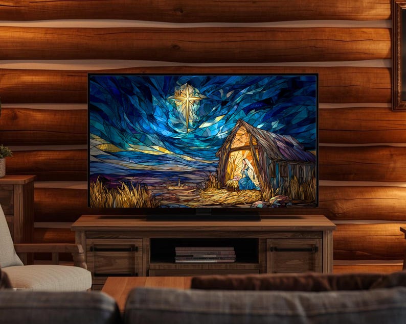 May include: A large flat-screen television displays a stained-glass style image of a nativity scene. The artwork features a star, a barn, and figures in a field, set against a blue and gold sky. The TV sits on a wooden cabinet.