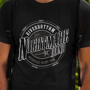 May include: Black crew neck t-shirt with a white graphic. The graphic reads "Riverbottom Nightmare Band 1977 Waterville Talent Show". The shirt is short-sleeved and made of a soft material.