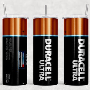 Pode incluir: Um conjunto de tr&ecirc;s canecas de a&ccedil;o inoxid&aacute;vel com tampas e canudos. As canecas apresentam um design que se assemelha a uma bateria Duracell, com uma parte superior marrom, corpo preto e as palavras "Duracell Ultra". As canecas t&ecirc;m uma faixa azul e o Duracell Powercheck.