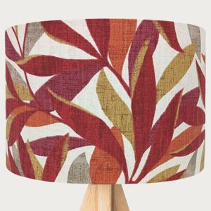 Peut inclure: Un abat-jour avec un motif de feuilles rouges, orange et dorées sur fond blanc.