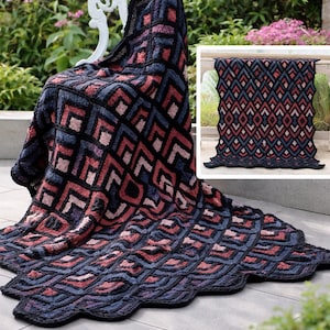 May include: A handmade blanket with a geometric pattern in black, navy, red, and pink. The blanket is draped over a white chair and spread out on a patio. The blanket's design features a repeating diamond pattern.