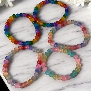 Handmade glass bead bracelets in vibrant rainbow and soft multicolor styles. Each bracelet features glossy round beads on a comfortable stretch cord, perfect for daily wear or gifting. Unique, colorful, and eye-catching accessories for any style or occasion.