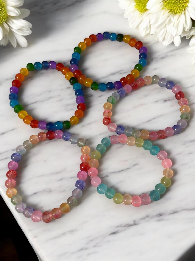Handmade glass bead bracelets in vibrant rainbow and soft multicolor styles. Each bracelet features glossy round beads on a comfortable stretch cord, perfect for daily wear or gifting. Unique, colorful, and eye-catching accessories for any style or occasion.