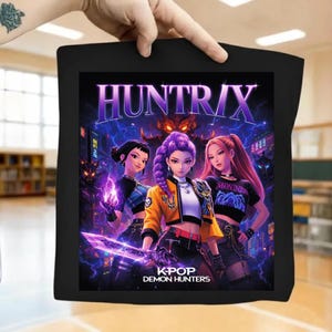 Peut inclure: Sac fourre-tout noir avec un graphisme vibrant de trois femmes de style anime aux cheveux violets, roses et noirs. L'image porte les inscriptions "HUNTRIX" et "K-POP DEMON HUNTERS" avec un fond d'éclairs et de figures démoniaques.