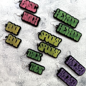 May include: A set of 10 pairs of Halloween-themed earrings. The earrings are made of acrylic and feature various spooky phrases like "Boo!" "Spooky" and "Trick or Treat".