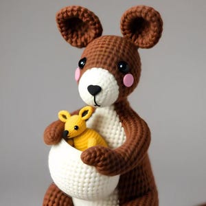May include: A brown crocheted kangaroo holding a yellow crocheted joey in its pouch. The kangaroo has pink cheeks and black eyes.