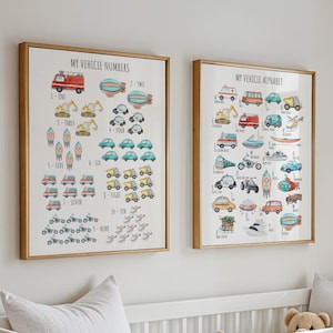 Op de afbeelding: Twee ingelijste prints met een lichte houten afwerking, met kleurrijke illustraties van voertuigen. Eén print toont voertuignummers van één tot en met tien, de andere het voertuigalfabet. De prints worden boven een wit babybedje weergegeven.