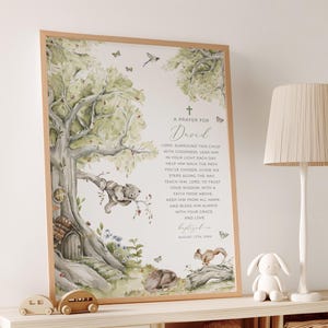 Puede incluir: Un cuadro enmarcado con una ilustración en acuarela de un árbol, un koala, ardillas y mariposas. La impresión incluye el texto "A Prayer for David" y una oración. El marco es marrón claro.