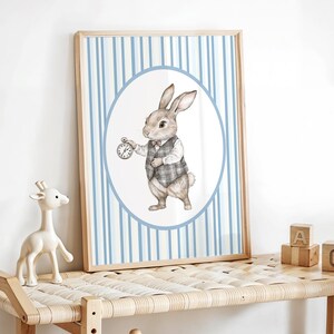May include: A framed print of a cartoon rabbit wearing a vest and holding a pocket watch. The rabbit is standing in a circle on a blue and white striped background.