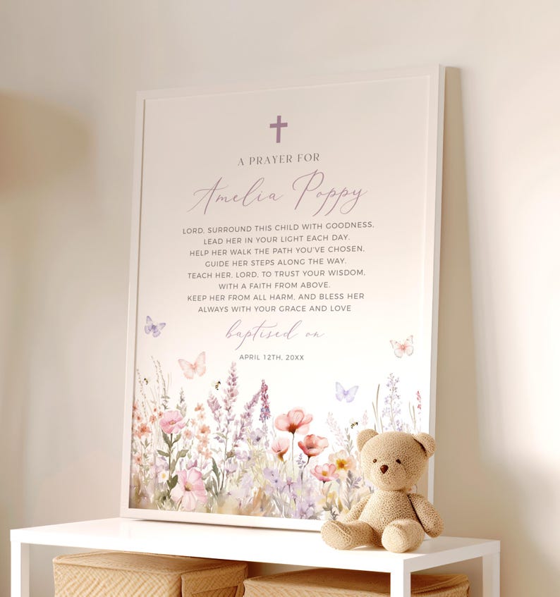 Op de afbeelding: Een ingelijste print met een bloemenontwerp en de tekst "A Prayer For Amelia Poppy". De print bevat een kruis en vlinders. Een kleine teddybeer staat op een witte plank.