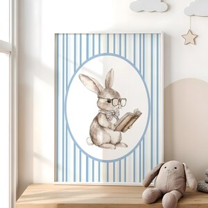 May include: A watercolor illustration of a brown bunny wearing glasses and a bow tie, holding a book. The bunny is in a white circle on a blue and white striped background.