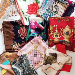 Peut inclure: Une collection de foulards carrés présentant des motifs variés, notamment des roses rouges, des chaînes dorées, des éléments équestres, des volutes cachemire et des carreaux dans des tons rouge, marron, rose, blanc et bleu, disposés en chevauchement.