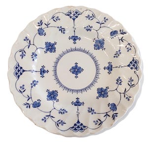 Può includere: Piatto in ceramica bianca con bordo smerlato, ornato da motivi floreali e di vite blu. Il piatto presenta un motivo floreale centrale e un bordo decorativo, creando un'estetica classica ed elegante. Ideale per servire cibo.