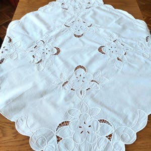 Puede incluir: Mantel de mesa de algodón blanco con delicados diseños florales bordados. El mantel tiene un borde festoneado y es perfecto para un comedor formal.