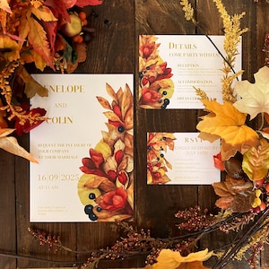 Può includere: Invito di nozze con un design floreale di foglie autunnali nei toni del rosso, arancione e giallo. L'invito include i nomi "ENELOPE AND COLIN" e la data "16 09 2025". Il set include dettagli e biglietti di RSVP.