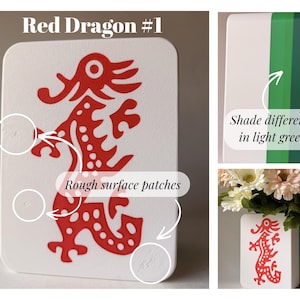 May include: A white rectangular block featuring a red dragon graphic and the text Red Dragon #1. The block displays rough surface patches and a side panel with varying shades of green. A small bouquet of artificial flowers sits behind the block.