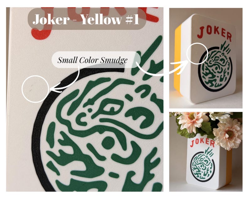 May include: A white rectangular vase with a yellow side panel, featuring the red text JOKER above a circular green graphic design. The surface displays a small color smudge near the black circular border, and the vase holds artificial flowers.
