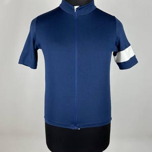 May include: Navy blue short-sleeve cycling jersey with a full-length zipper and a high collar. The jersey features a white stripe on the left sleeve. The jersey is displayed on a mannequin.