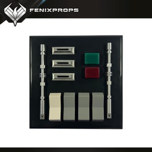 May include: A black control panel with various buttons, switches, and lights. The panel features silver bars, rectangular buttons, and green and red square lights. The text "FENIXPROPS" is visible at the top.