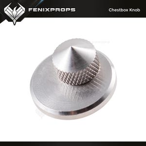 Könnte beinhalten: Ein silberner Truhenknopf mit strukturiertem Griff und konischer Oberseite. Der Knopf ist auf einer kreisförmigen Basis montiert. Der Text "FENIXPROPS" und "Chestbox Knob" sind sichtbar.