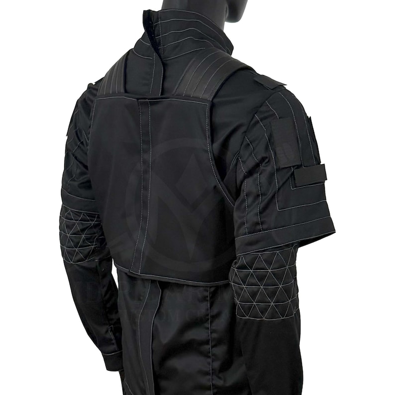 Puede incluir: Chaqueta t&aacute;ctica negra con cuello alto y detalles de costuras geom&eacute;tricas. La chaqueta presenta una superposici&oacute;n tipo chaleco y m&uacute;ltiples bolsillos. El dise&ntilde;o incluye un patr&oacute;n sutil y repetitivo en la espalda y las mangas.