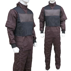 May include: A brown jumpsuit with a high collar and black accents. The outfit includes a padded vest and long sleeves with black cuffs. The pants have a straight leg design. The outfit is displayed on a mannequin.