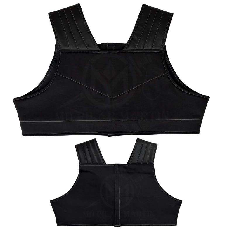 May include: Two black padded vests with adjustable straps. The vests have a simple design with a V-shaped seam in the front.