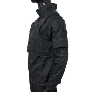 Puede incluir: Chaleco t&aacute;ctico negro y camisa de manga larga. El chaleco presenta m&uacute;ltiples bolsillos y paneles, con costuras reforzadas. La camisa tiene un cuello alto y parches reforzados en los hombros y codos. El conjunto est&aacute; dise&ntilde;ado para protecci&oacute;n y durabilidad.