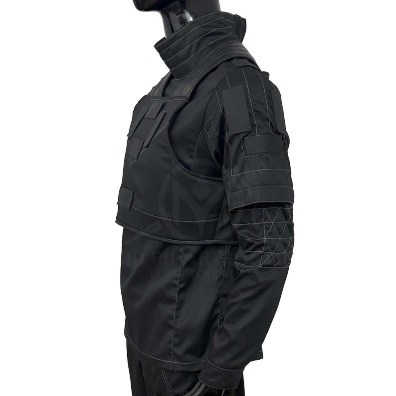 Puede incluir: Chaleco t&aacute;ctico negro y camisa de manga larga. El chaleco presenta m&uacute;ltiples bolsillos y paneles, con costuras reforzadas. La camisa tiene un cuello alto y parches reforzados en los hombros y codos. El conjunto est&aacute; dise&ntilde;ado para protecci&oacute;n y durabilidad.