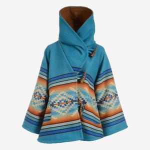 May include: A turquoise hooded poncho with a Southwestern-inspired pattern in shades of orange, blue, and cream. The poncho features wooden toggle closures and a brown interior lining. The design includes geometric shapes and horizontal stripes.