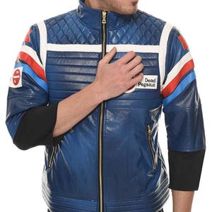 May include: Blue leather jacket with a quilted pattern, white stripes, and red and blue accents. Features a gold zipper and the text "Dead Pegasus". The jacket has black sleeves and a stand-up collar.