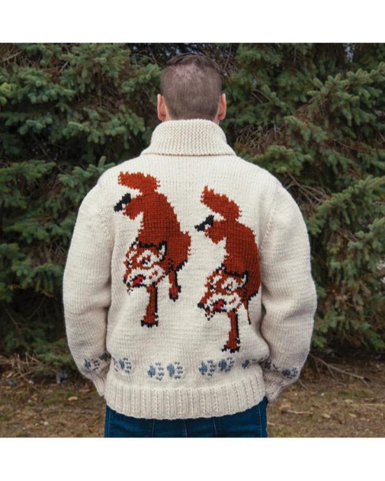 May include: Cream-colored knit sweater featuring a large, detailed design of two foxes in shades of brown and white on the back. The sweater has a ribbed collar and cuffs, with a small floral pattern near the bottom hem. The sweater is worn by a person.