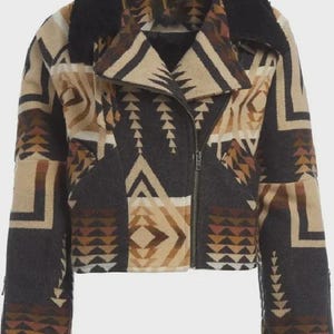 May include: A cropped jacket featuring a black, tan, and brown geometric pattern. The garment has a black faux fur collar, a diagonal front zipper closure, long sleeves with zippered cuffs, and a structured lapel design with a textured finish.