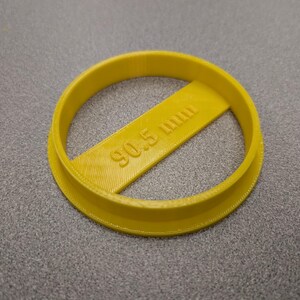 May include: A yellow plastic circle cookie cutter with the text "90.5 mm" printed on it.