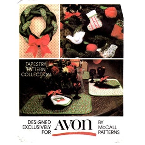 May include: A vintage tapestry pattern collection featuring Christmas-themed crafts. The image showcases a green and red wreath, Christmas tree ornaments, and placemats with matching coasters. The text reads "Designed Exclusively for Avon by McCall Patterns."