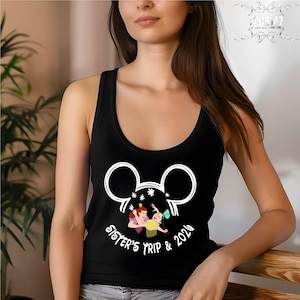 May include: A black tank top featuring a white graphic of a mouse ear silhouette containing an illustration of two animated characters in a struggle, with the text "SISTER'S TRIP & 2020" printed in white lettering underneath the graphic.