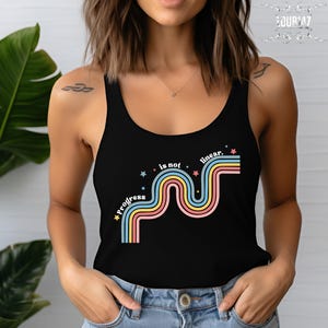 May include: A black tank top featuring a graphic design with the text "progress is not linear." The design includes a series of wavy, multi-colored stripes in shades of blue, yellow, and pink, accented by small, scattered star shapes in various colors.
