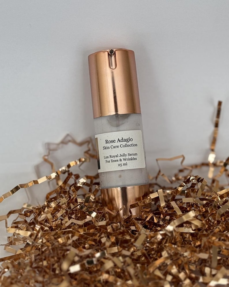 May include: A rose gold bottle of serum labelled "Rose Adagio Skin Care Collection Lux Royal Jelly Serum For lines & Wrinkles 25 ml".