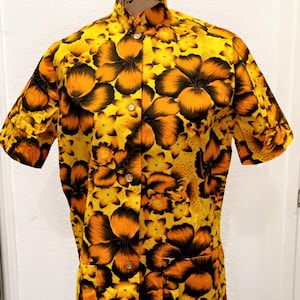 May include: A yellow short-sleeved button-up shirt with a black and orange floral print.