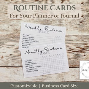 May include: Two white routine cards with handwritten text, labeled "Weekly Routine" and "Monthly Routine." The cards are for a planner or journal and include checklists for home tasks. The background is a light brown wood grain.