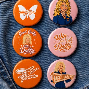 May include: Six circular pinback buttons featuring Dolly Parton imagery. Three are orange with white graphics including a butterfly, the text Good Golly Miss Dolly, and Dolly Forever. Three are pink with illustrations of Dolly and the text Win for Dolly.