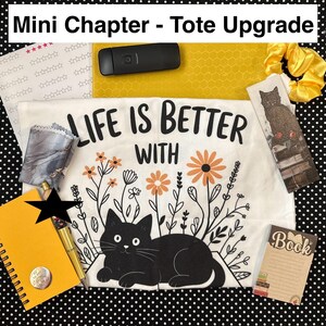 May include: A collection of stationery and accessories, including a white t-shirt with a black cat graphic and the text "LIFE IS BETTER WITH". Also includes a yellow notebook, pen, bookmark, and scrunchie, all arranged on a black and white polka dot background.