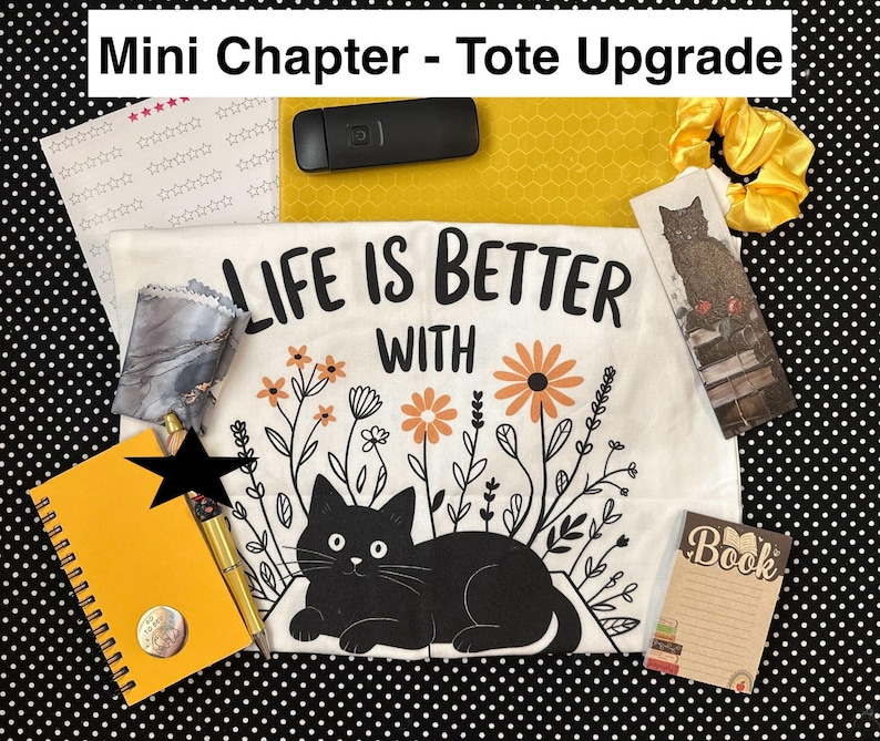May include: A collection of stationery and accessories, including a white t-shirt with a black cat graphic and the text "LIFE IS BETTER WITH". Also includes a yellow notebook, pen, bookmark, and scrunchie, all arranged on a black and white polka dot background.