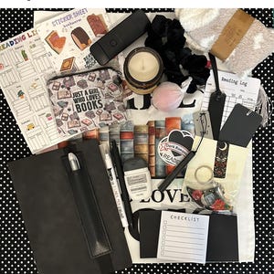 May include: A curated gift box for book lovers, featuring a black journal with pen, candle, stickers, reading log, and other accessories. The box includes a variety of items with a dark romantic theme, perfect for readers.