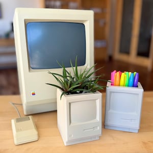 May include: A vintage-style computer monitor, a planter with a succulent, and a pen holder, all in a cream color. The planter and pen holder are shaped like miniature computers. A computer mouse is also present.