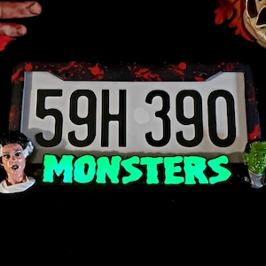 May include: A black and red Halloween-themed license plate with the text "59H 390 MONSTERS" in white and green glow-in-the-dark letters.