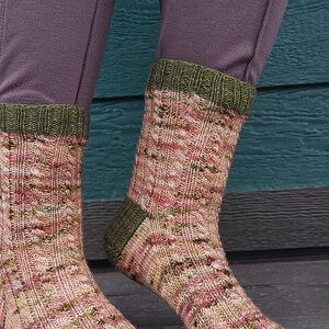 May include: A pair of knitted socks with a green and pink speckled pattern. The socks have a green cuff and toe.