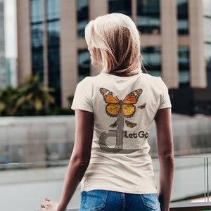 May include: A white t-shirt with a butterfly graphic and the text "Let Go" on the back. The butterfly is orange, yellow, and black.