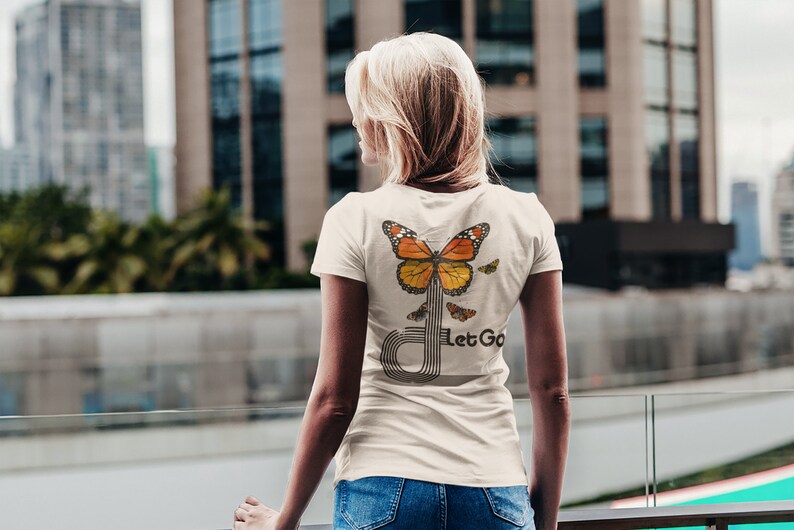 May include: A white t-shirt with a butterfly graphic and the text "Let Go" on the back. The butterfly is orange, yellow, and black.